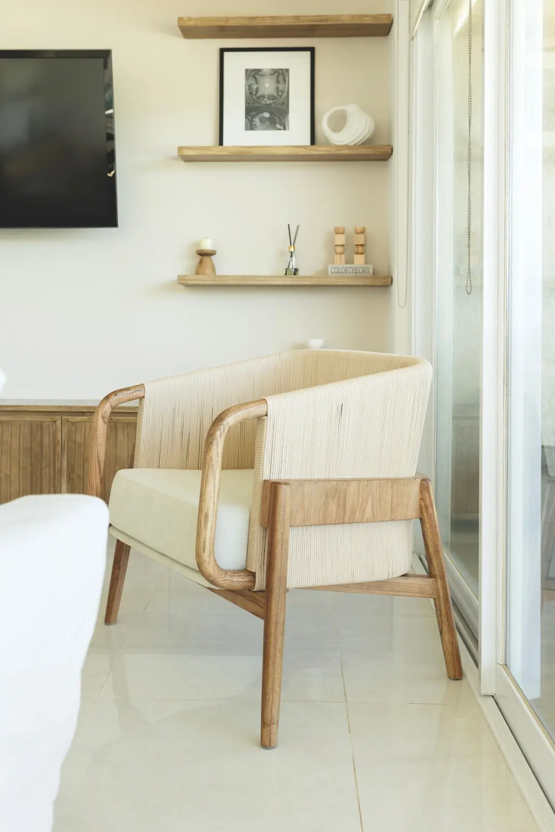 Poltrona de madera con respaldo tejido en un living luminoso