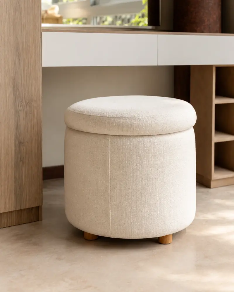 Puff redondo tapizado en tela clara, con patas de madera
